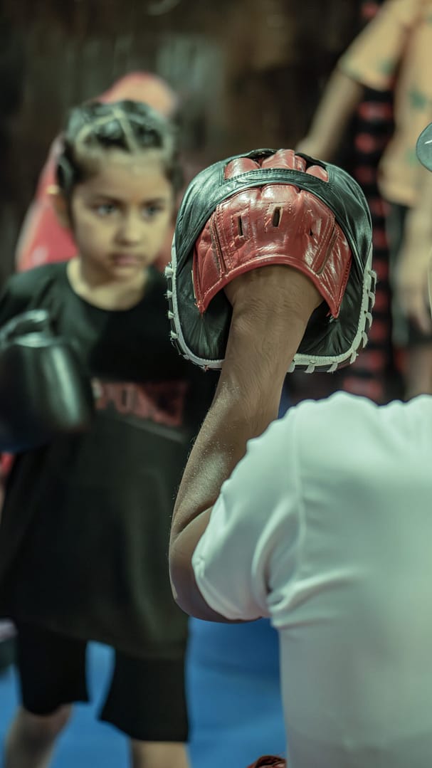 Little girl hitting boxing pads