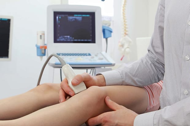 Calf Injury Diagnosis Doctor performing an ultrasound scan of a patient's calf to diagnose a muscle tear