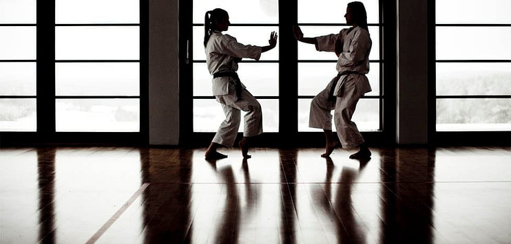 Karate practitioners in white gi performing a precise kick with focused expression Karate practitioners in white gi performing a precise kick with focused expression