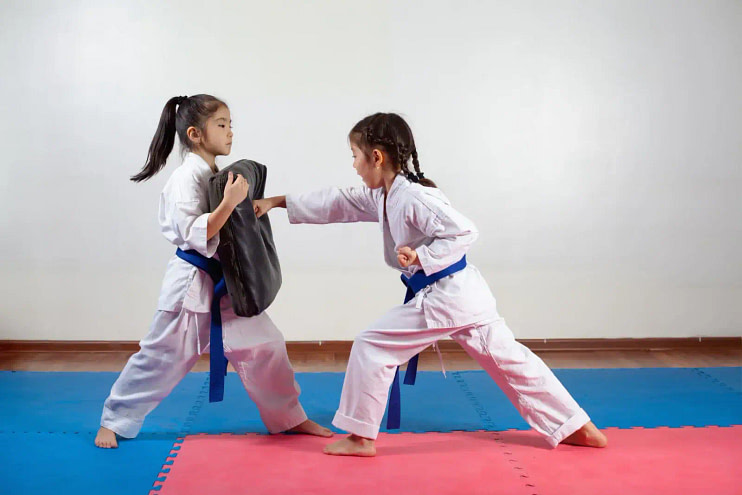 Two young girls practicing thier karate striking